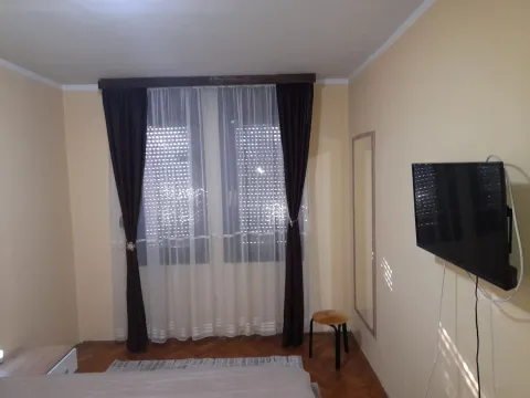 Spavaća soba sa televizorom na zidu i zavjesama na prozorima. - image 4