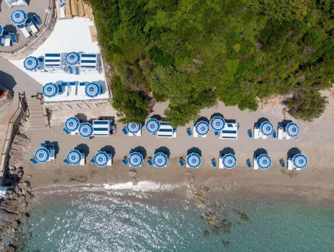 Pogled iz vazduha na uređenu plažu sa ležaljkama i suncobranima pored mora. - image 6