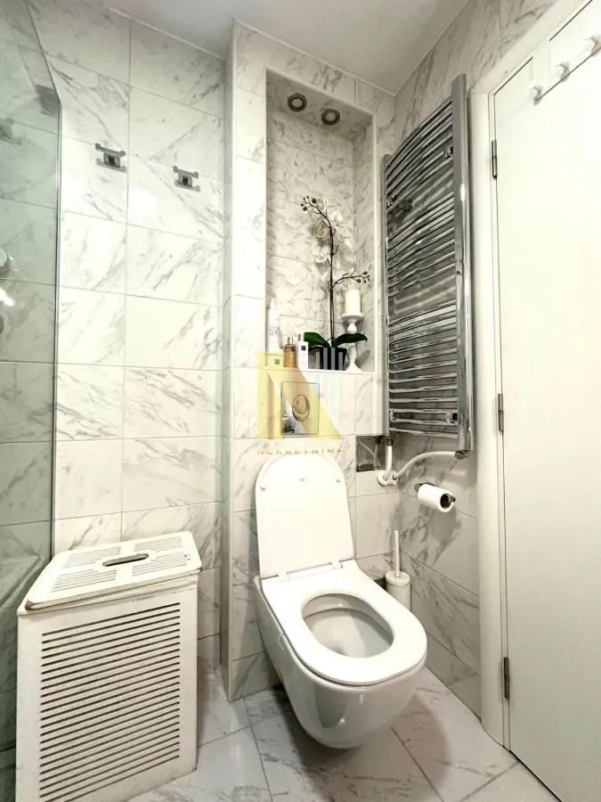 Moderno opremljeno kupatilo sa wc šoljom i mermernim pločicama.