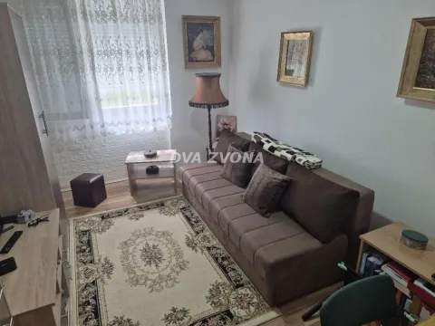 Dnevna soba sa braon trosedom, tepihom i policama. - image 7