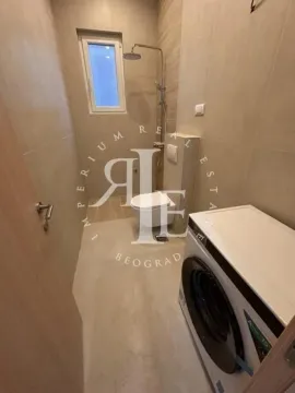 Modernly equipped bathroom with a shower, toilet, and washing machine. - image 9