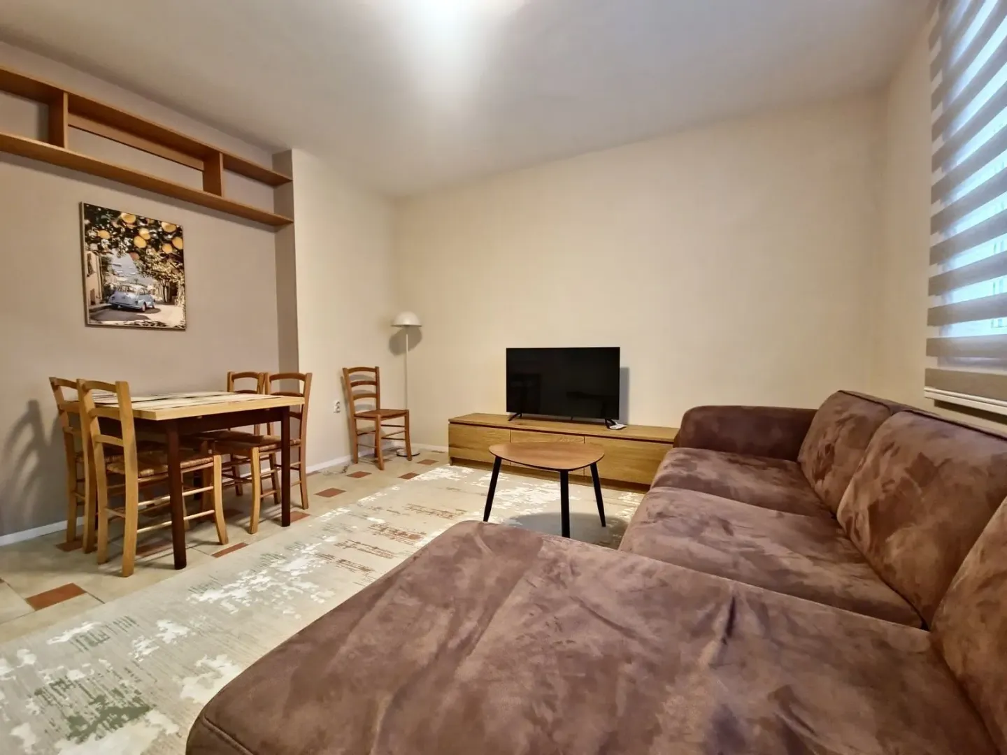 Living room with sofa, TV and dining table.