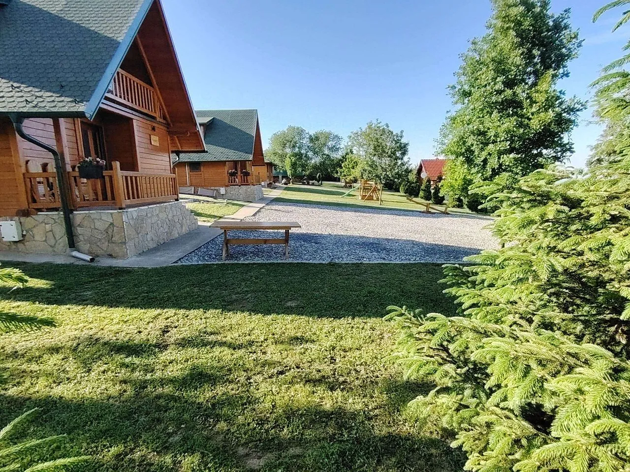 Pogled na dvorište sa drvenim kućicama i zelenilom.