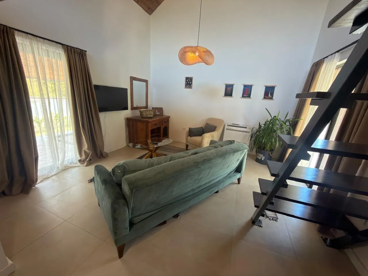 Spacious living room with a sofa, TV, and stairs leading to the gallery.