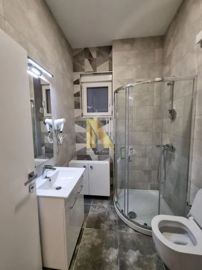 Moderno kupatilo sa tuš kabinom, umivaonikom i WC šoljom.