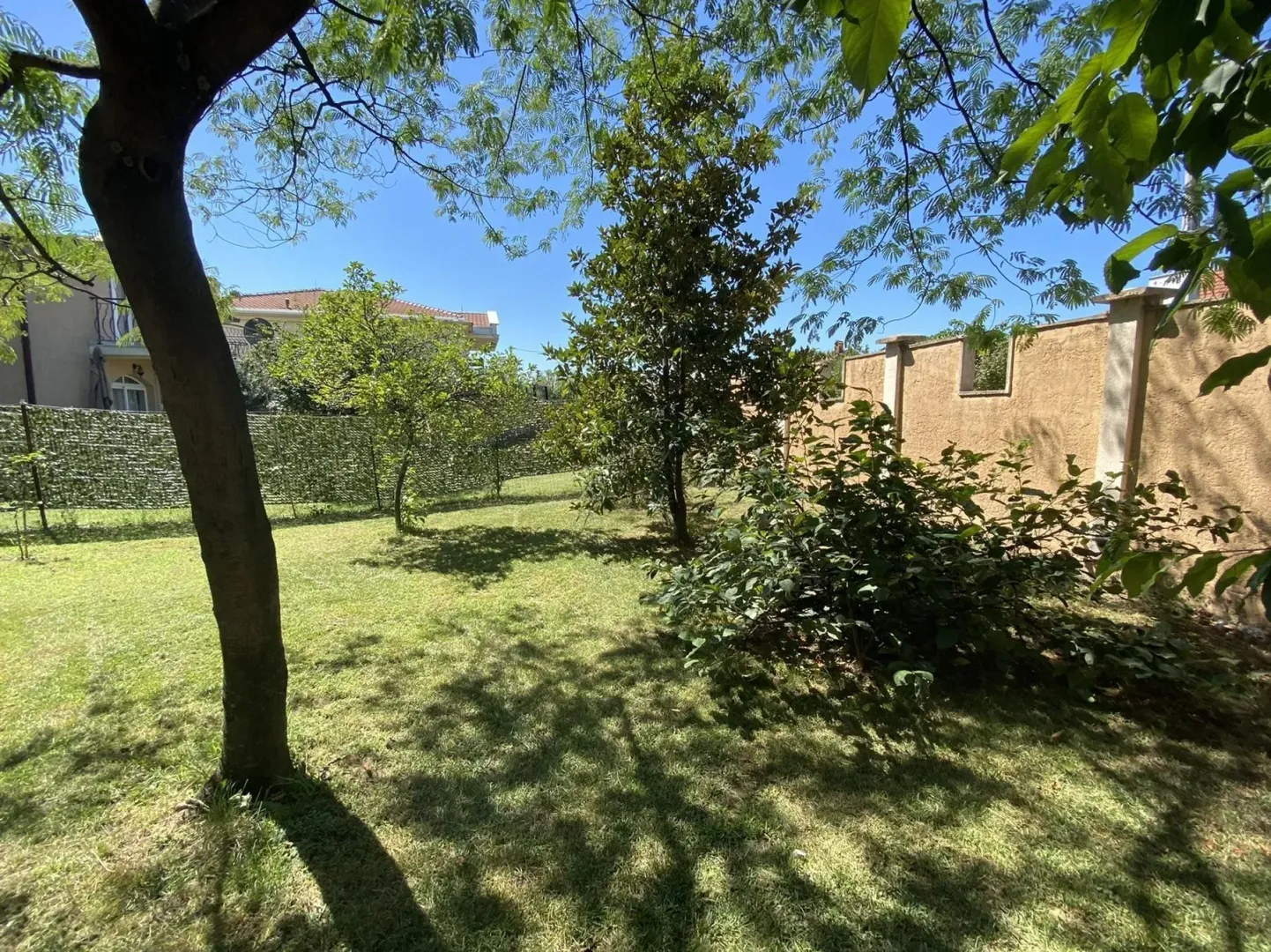 A spacious, well-maintained yard with green lawn and trees.