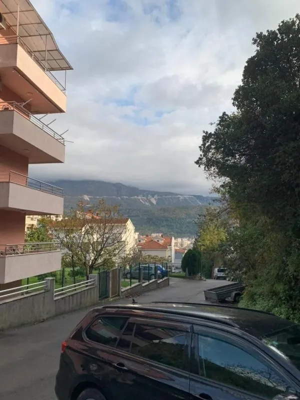 View of the driveway and surrounding buildings with hills in the background.