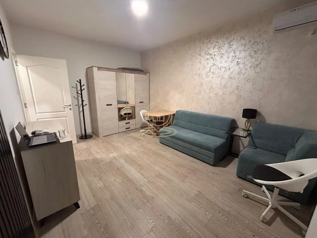 Living room furnished with a sofa set, wardrobe, and a desk.