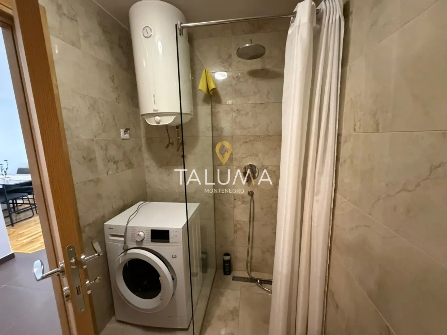 Tiled bathroom featuring a walk-in shower and a washing machine.