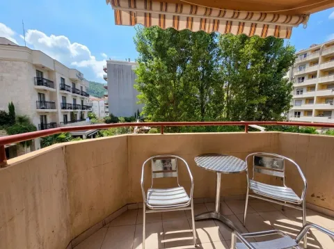 Namješten balkon sa stolom, stolicama i tendom, sa pogledom na okolne zgrade i zelenilo. - image 8