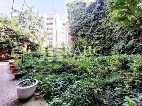 Green courtyard with vegetation and pots in front of an apartment building. - image 18