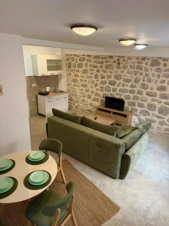 Living room with a sofa, dining area, and a stone wall.