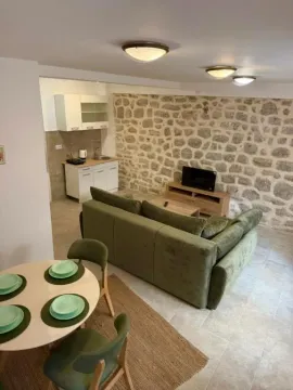 Living room with a sofa, dining area, and a stone wall. - image 19