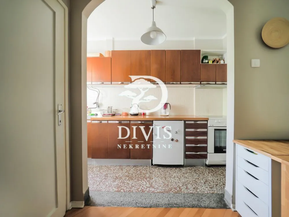 View of the kitchen with wooden cabinets through an arched doorway.