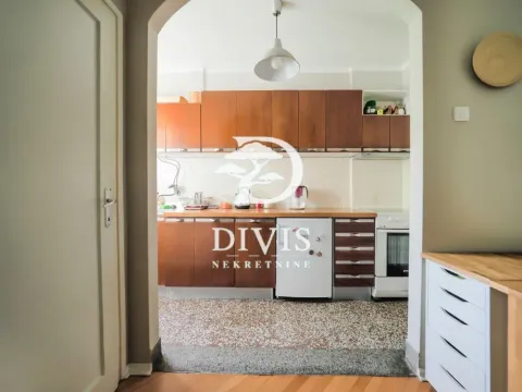 View of the kitchen with wooden cabinets through an arched doorway. - image 14