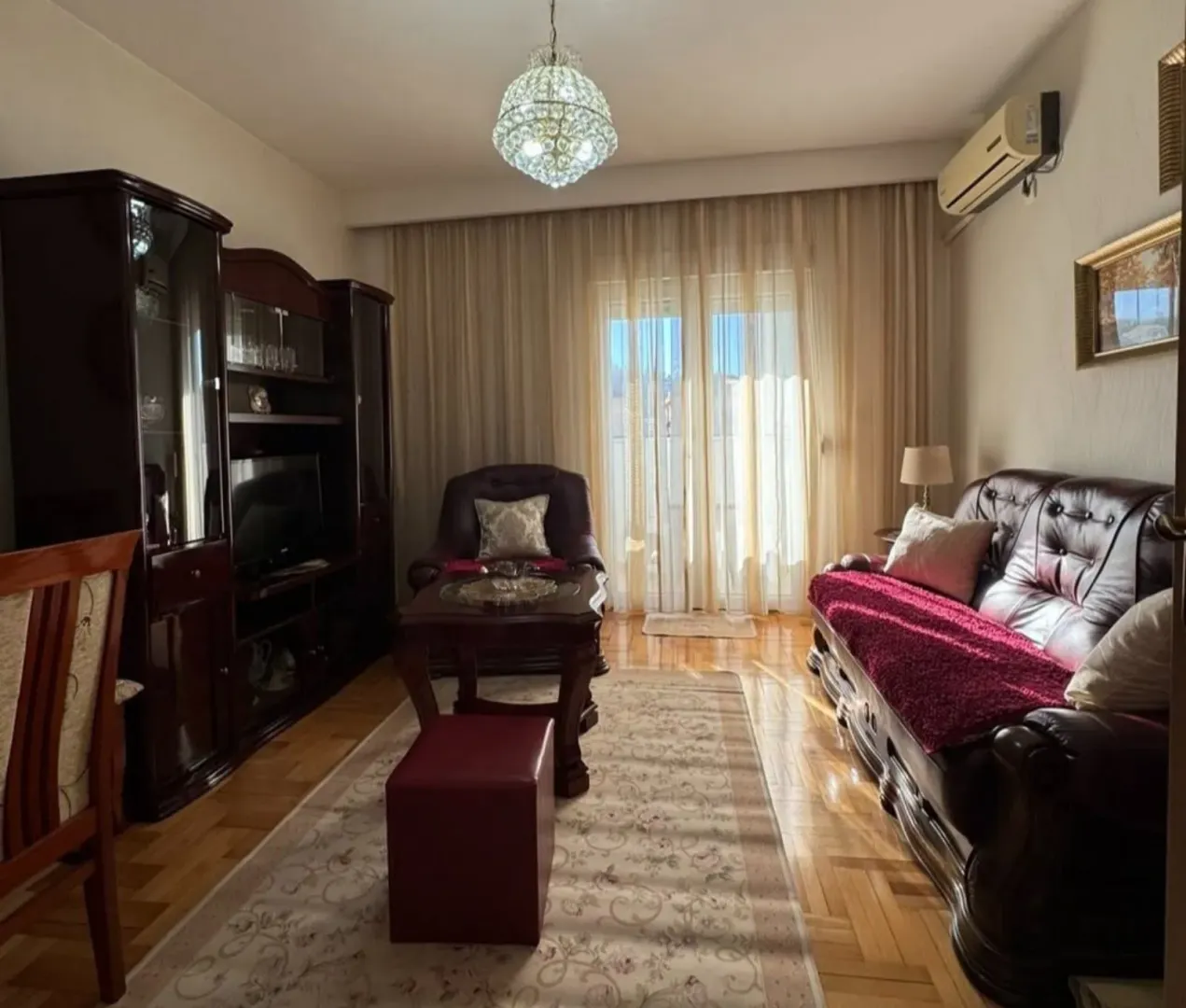 Classically furnished living room with leather seating and wooden cabinets.