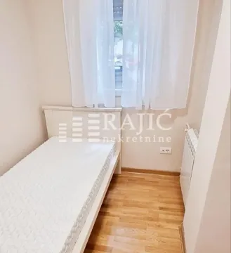 Smaller bedroom with a bed and a window with white curtains. - image 5
