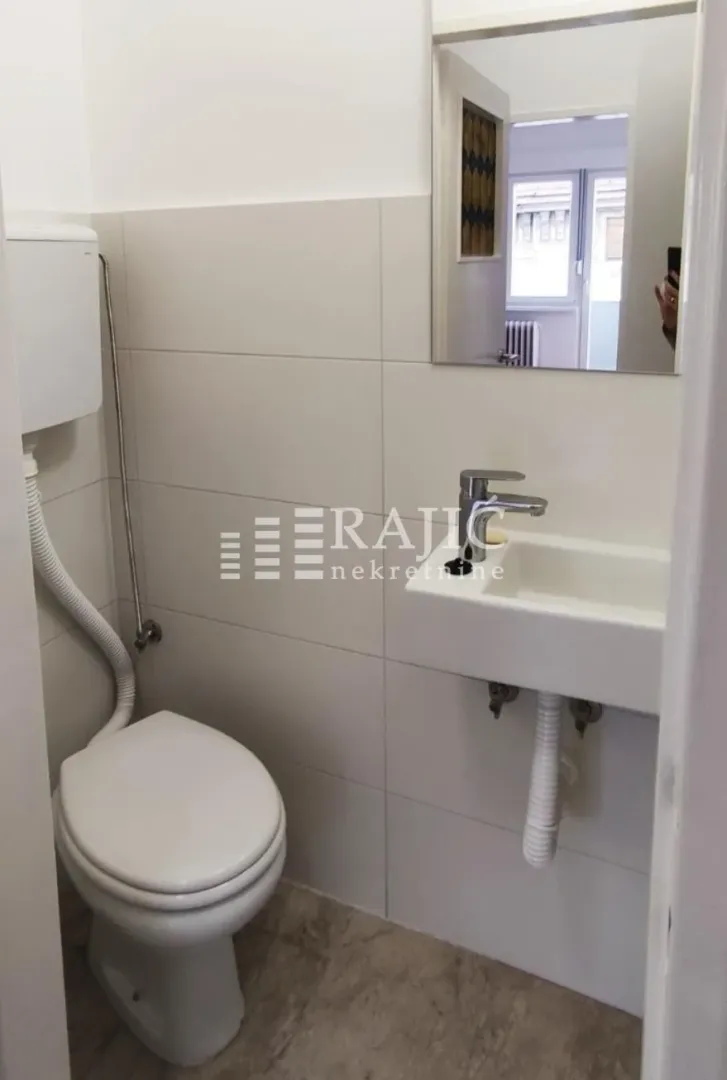Small bathroom with toilet, washbasin, and mirror.