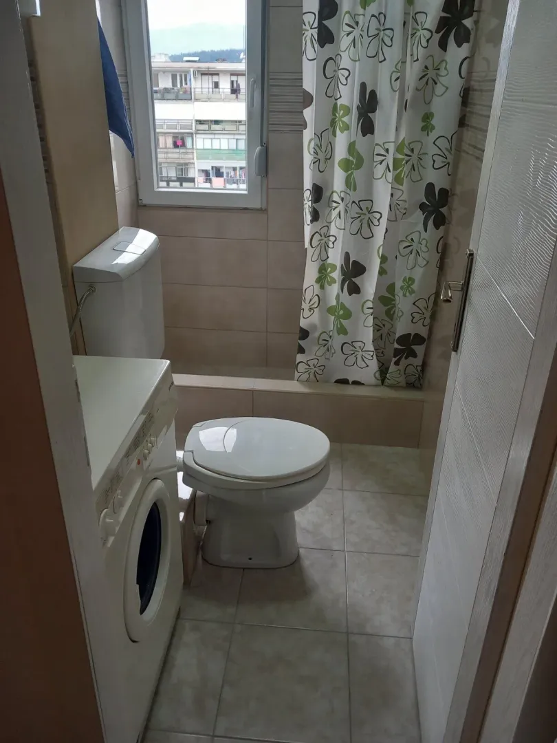 Smaller bathroom with a toilet, shower cabin, and washing machine.