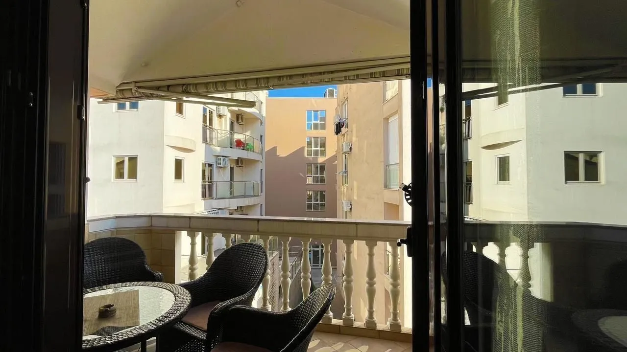Covered balcony with patio furniture and a view of surrounding buildings.