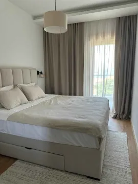 Uređena spavaća soba sa bračnim krevetom i prozorom sa zavjesama. - image 6