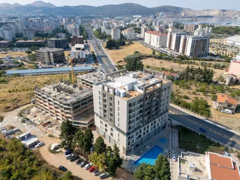 Pogled iz vazduha na stambenu zgradu sa bazenom i okolnim gradskim pejzažem. - image 17