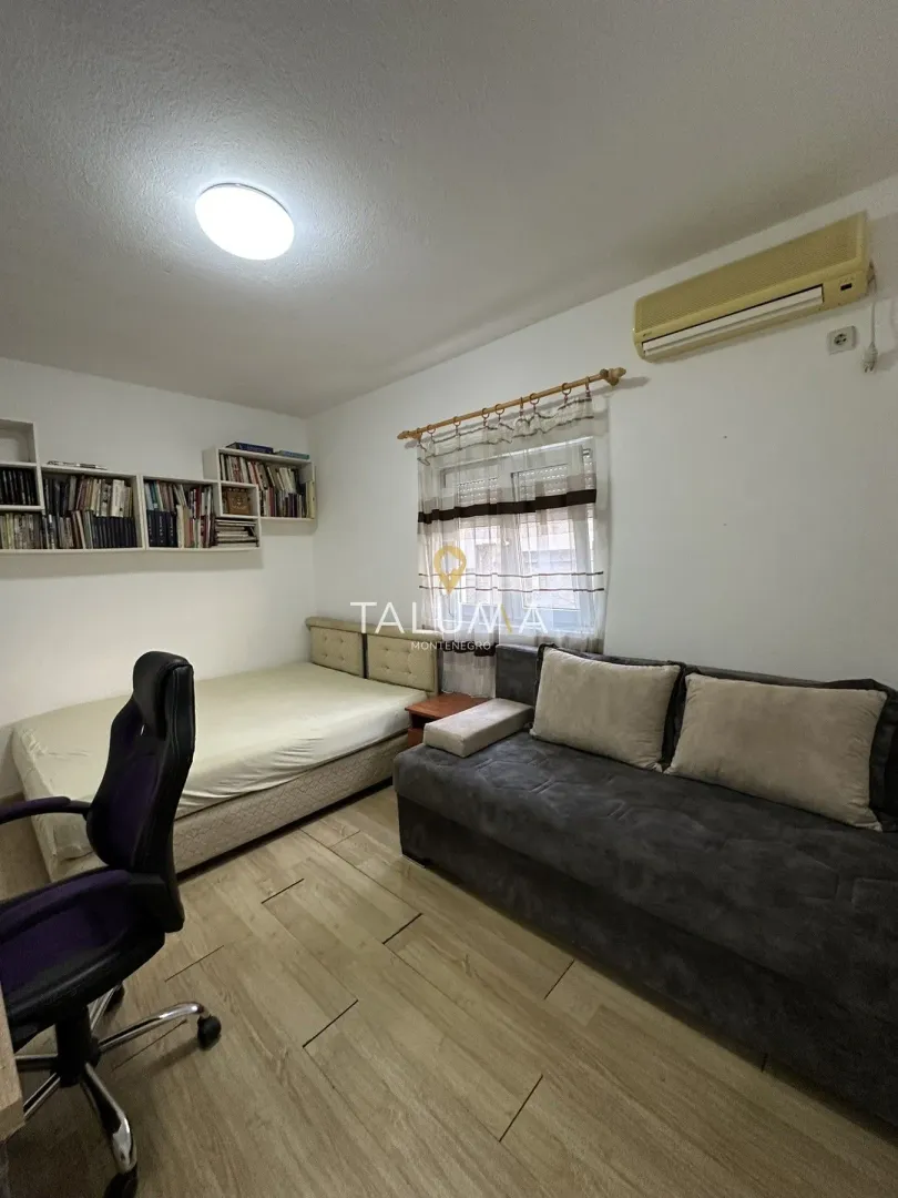 Bedroom with a bed, sofa, office chair, and wall bookshelves.
