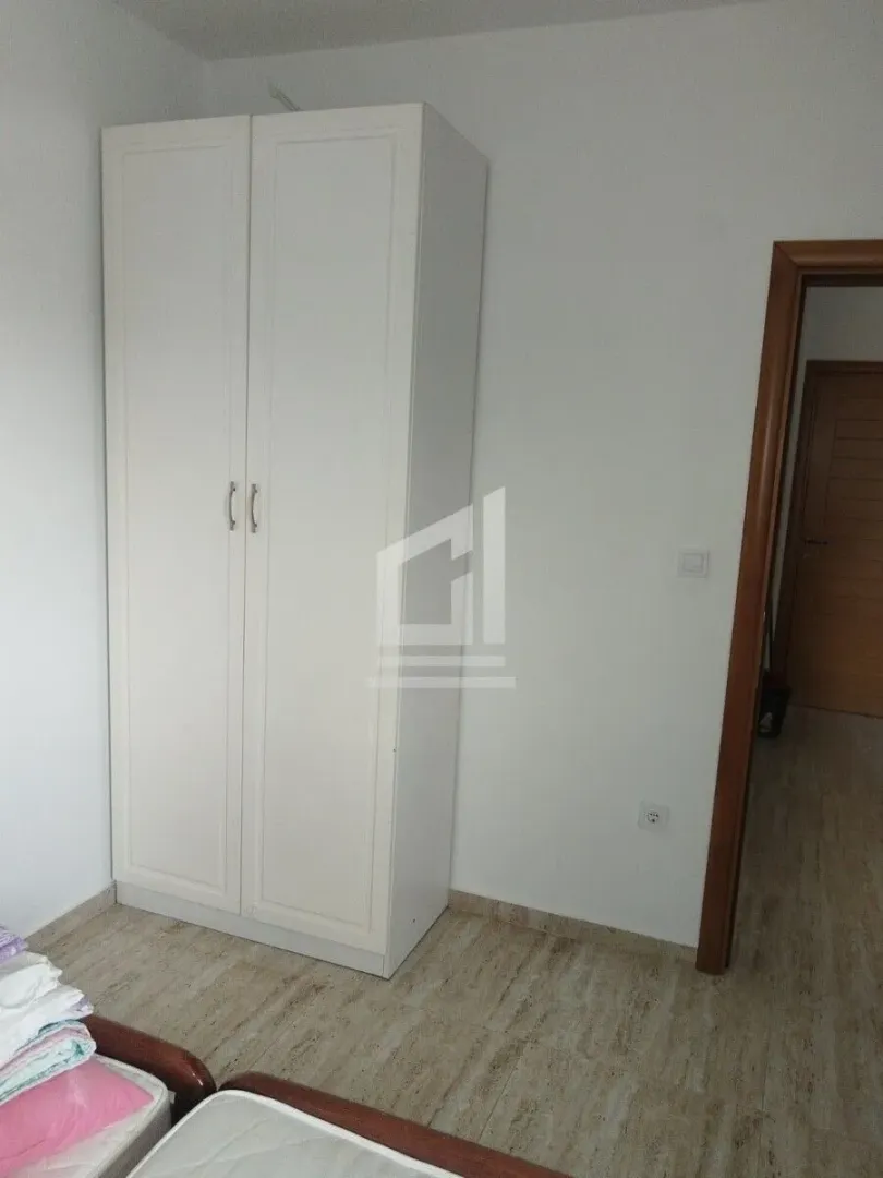 Manja spavaća soba sa bijelim garderoberom i krevetom.