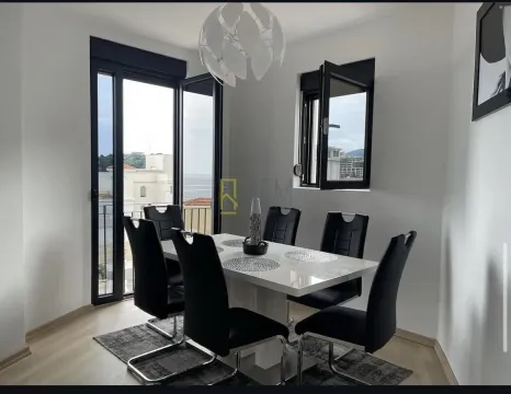 Dining room with a white table, black chairs, and access to a terrace with a sea view. - image 3