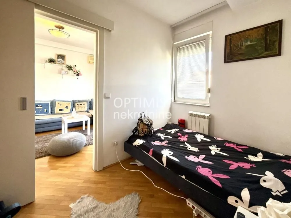 Manja spavaća soba sa krevetom i pogledom na susednu prostoriju kroz klizna vrata.
