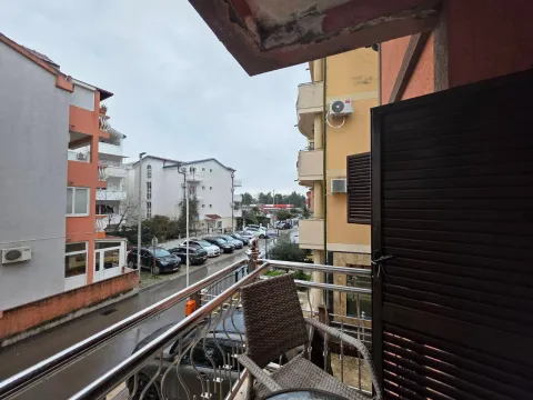 View from the balcony overlooking surrounding buildings and a street with parking. - image 13