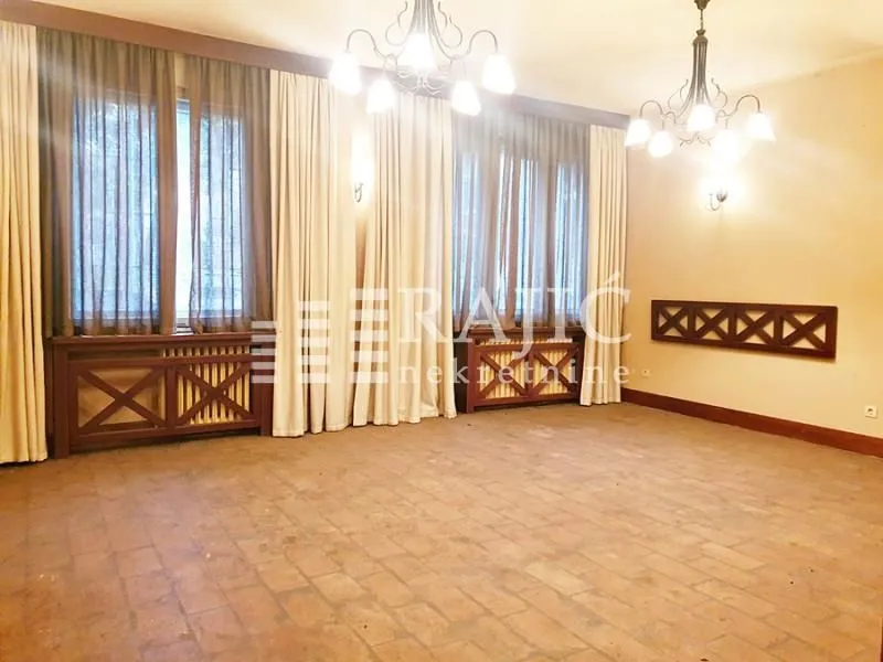 Spacious empty room with large windows and chandeliers.