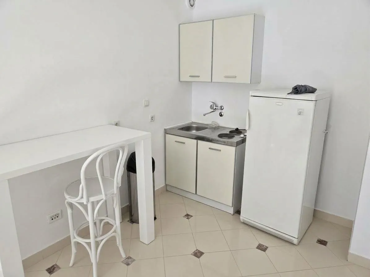 Small white kitchen with a refrigerator and a dining table.