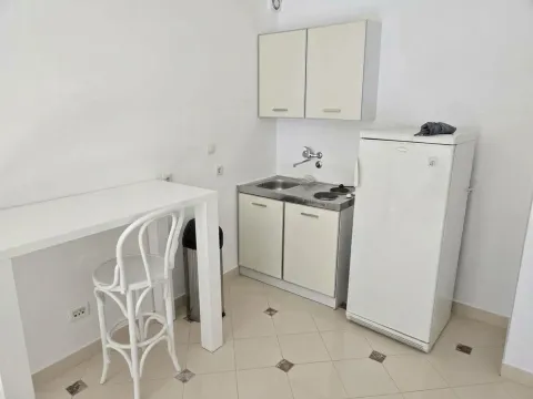 Small white kitchen with a refrigerator and a dining table. - image 6
