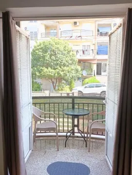 Namješten balkon sa stolom i stolicama i pogledom na ulicu. - image 9