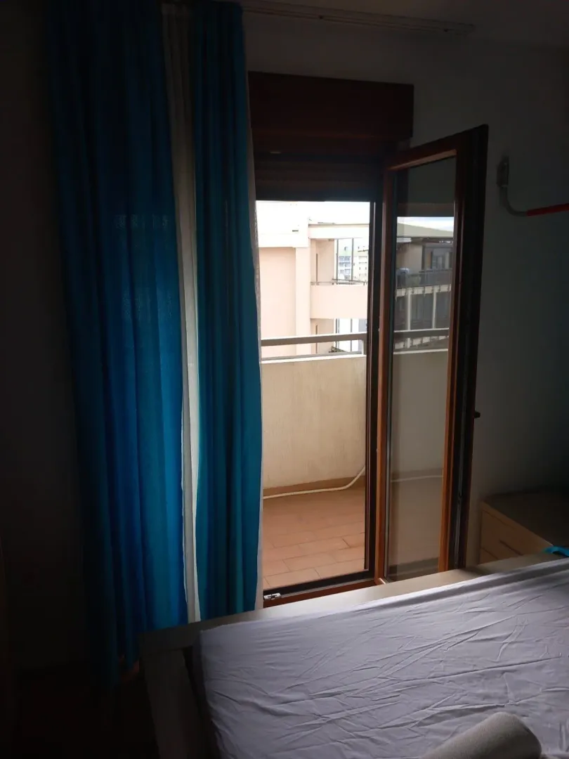 Spavaća soba sa izlazom na balkon i plavim zavjesama.