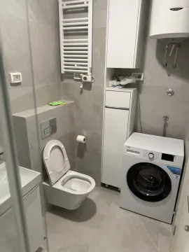 A modern bathroom equipped with a washing machine and gray ceramic tiles. - image 5