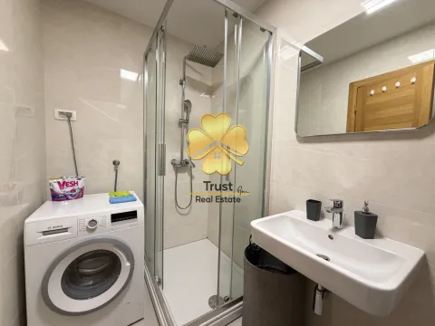 Modern bathroom with a shower cabin, washbasin, and washing machine. - image 9