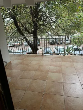 Prostrana popločana terasa sa metalnom ogradom i pogledom na parkiralište i drveće. - image 11