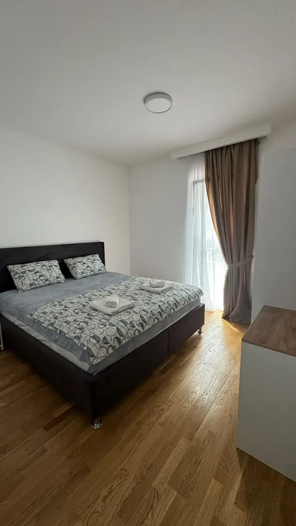 Uređena spavaća soba sa bračnim krevetom i drvenim podom.