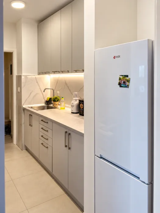 Small kitchen with light-colored cabinets and a white refrigerator.