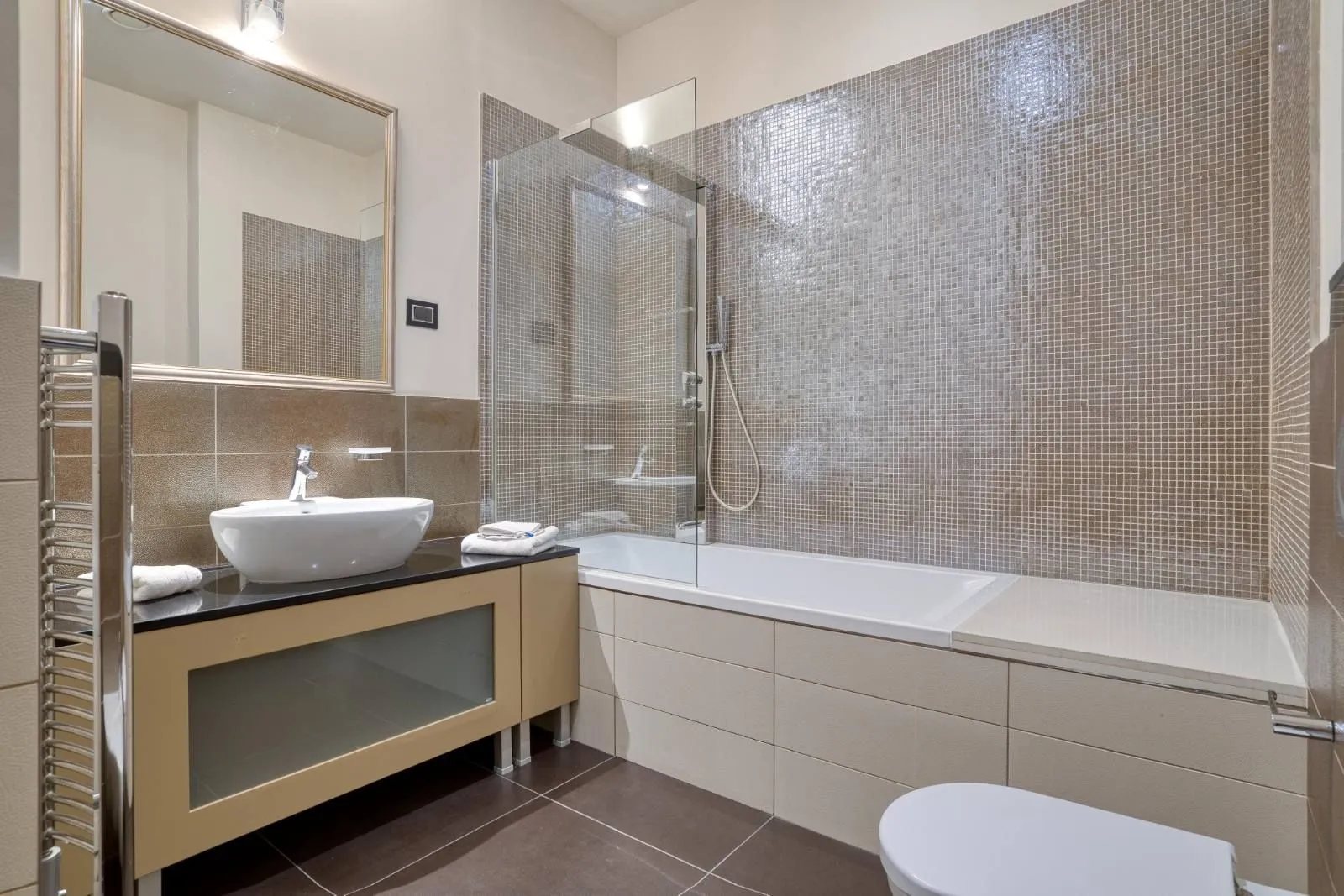 Modern bathroom with washbasin, bathtub, and glass partition.
