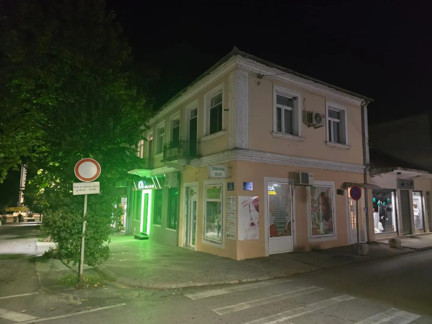 Noćni pogled na spoljašnjost poslovno-stambene zgrade sa lokalima u prizemlju.