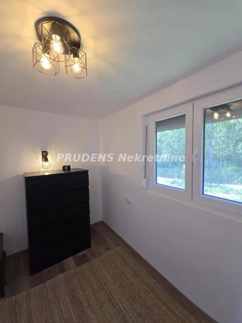 Small room with a chest of drawers and a window overlooking nature.