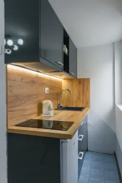 Smaller kitchen with dark cabinets and a wooden countertop. - image 3