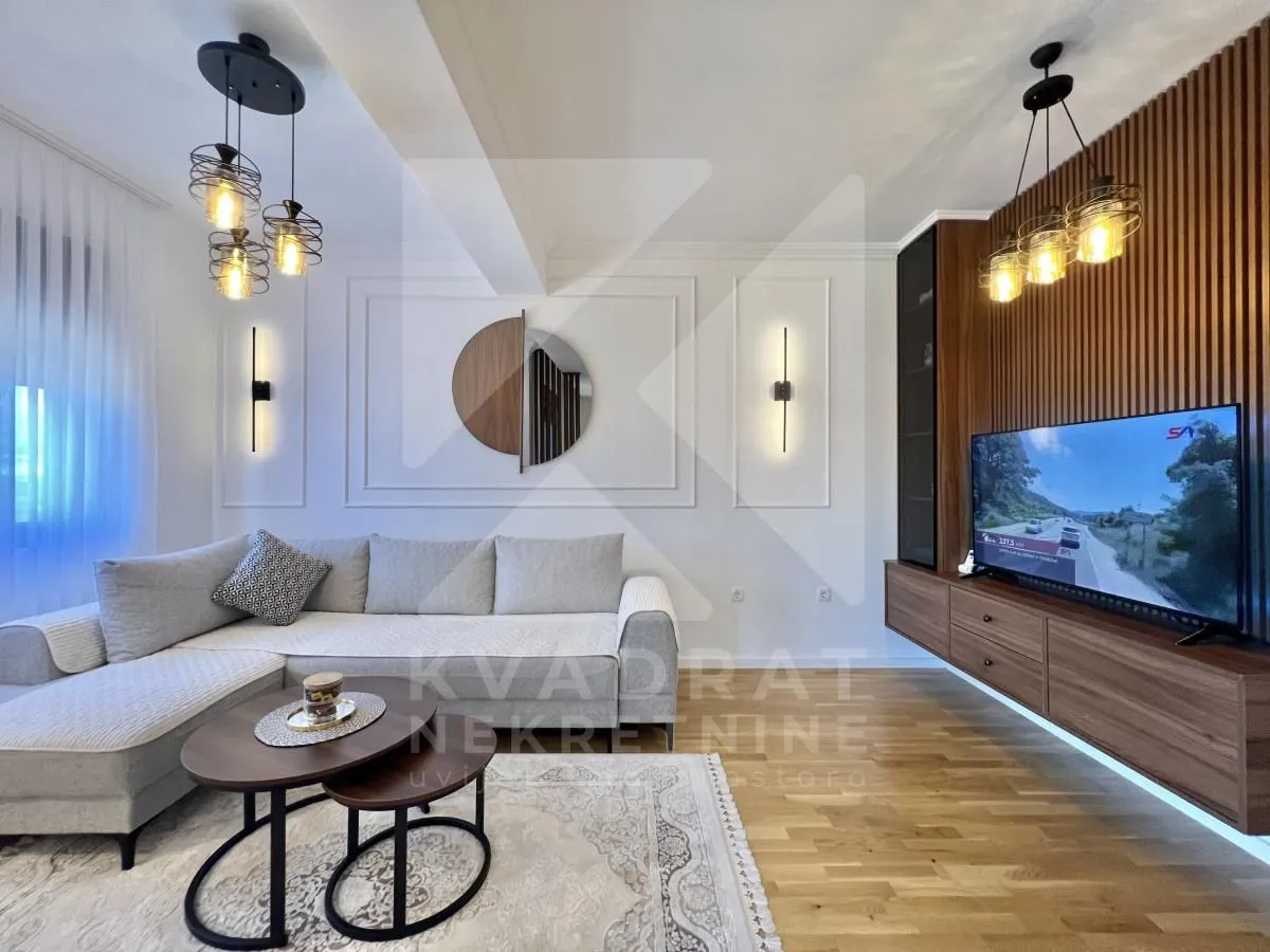 Modern living room with a sectional sofa, wood wall paneling, and a TV.