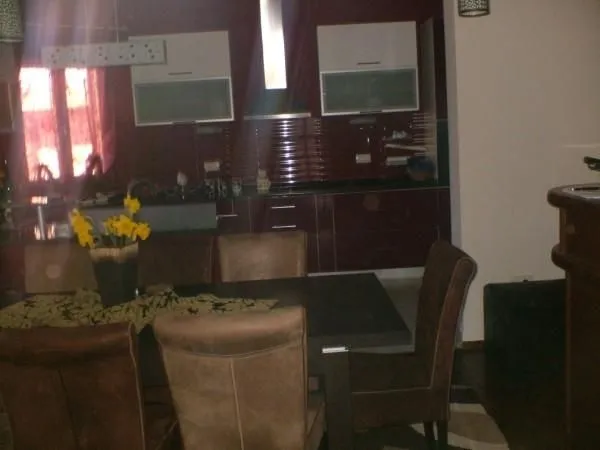 A kitchen with a dining table and chairs in dark tones.