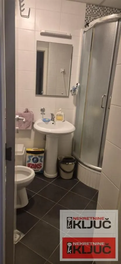 Manje kupatilo sa umivaonikom, WC šoljom i tuš kabinom.