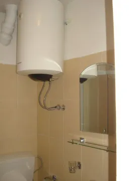 Part of a bathroom with a water heater, mirror, and tiles. - image 9