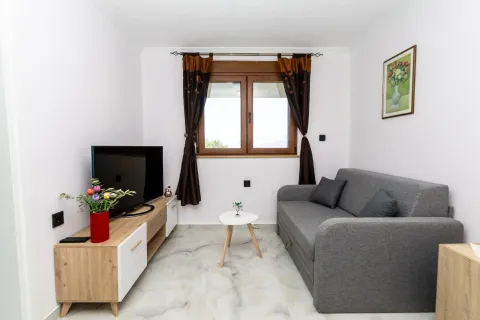 Small living room with a grey sofa, TV unit, and window. - image 9